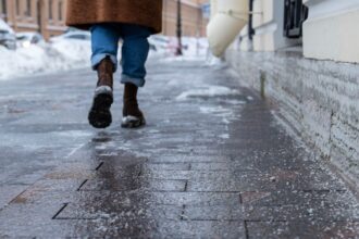 Jeges járda télen, csúszásveszélyes burkolaton sétáló ember