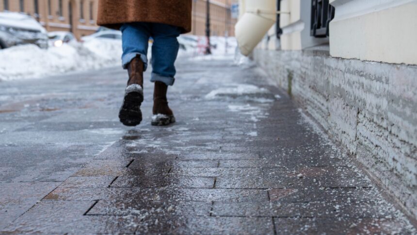 Jeges járda télen, csúszásveszélyes burkolaton sétáló ember