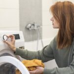 Mosógépet beállító nő